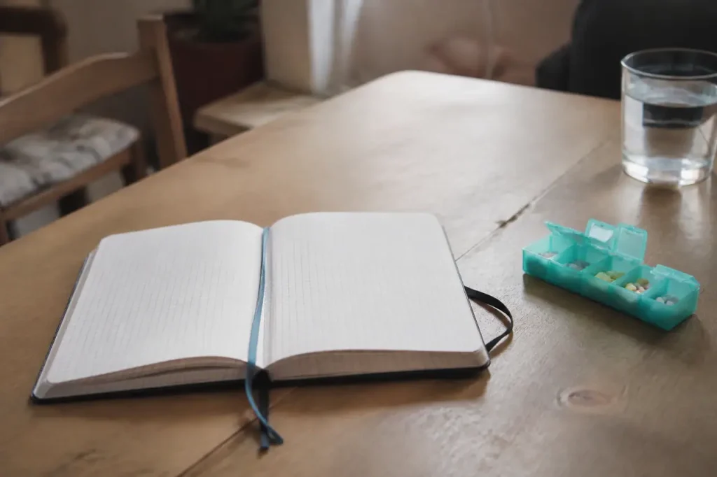 Carnet ouvert avec notes et pilulier sur une table